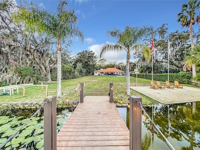 dock area with a lawn and a water view