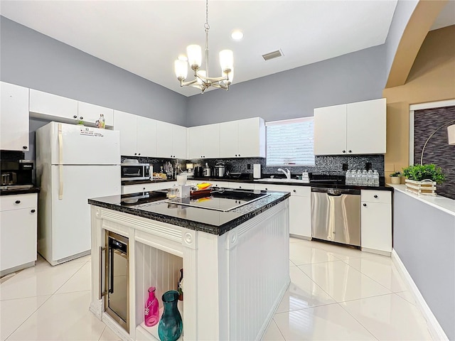 kitchen with appliances with stainless steel finishes, light tile patterned floors, white cabinetry, and a kitchen island