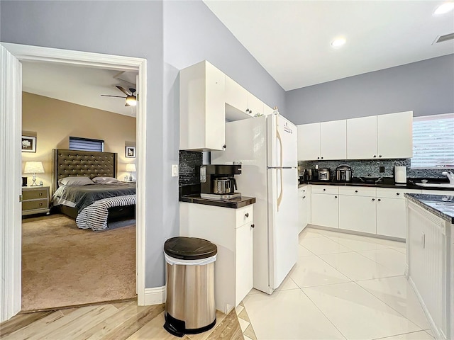 kitchen featuring white fridge, white cabinetry, and backsplash