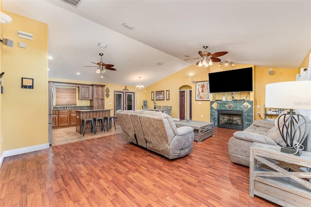 living room featuring a fireplace, light wood-type flooring, vaulted ceiling, and a chandelier