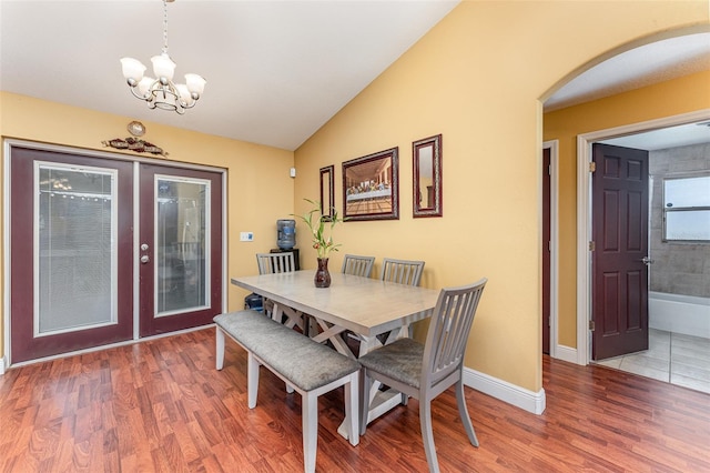 dining area with a notable chandelier, vaulted ceiling, and hardwood / wood-style flooring