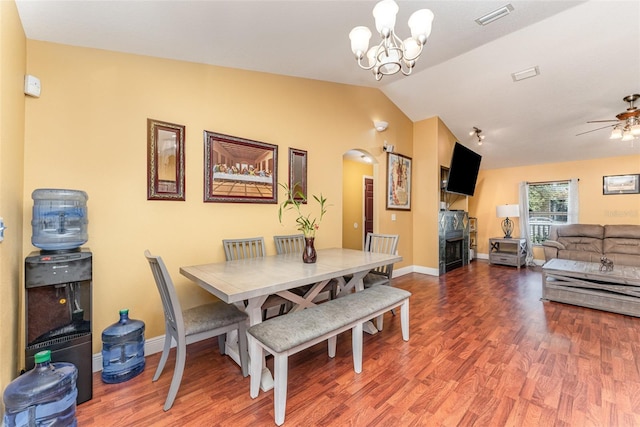 dining room featuring ceiling fan with notable chandelier, hardwood / wood-style flooring, and vaulted ceiling