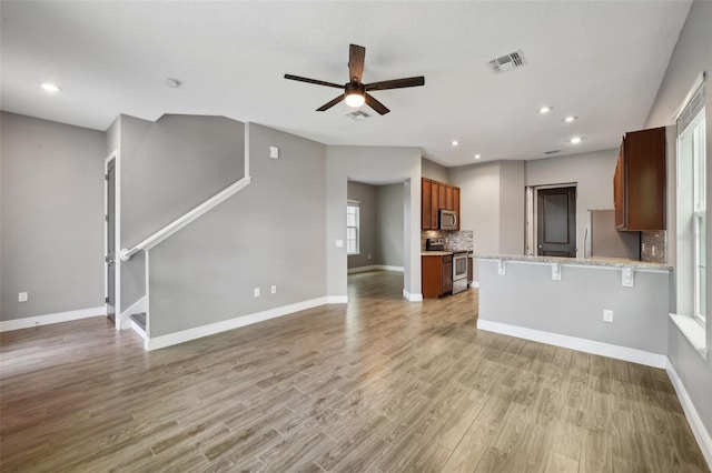 unfurnished living room featuring ceiling fan, a healthy amount of sunlight, and light hardwood / wood-style flooring