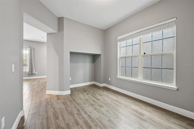 spare room featuring light hardwood / wood-style floors and a textured ceiling