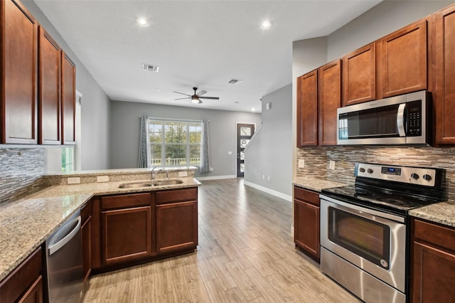 kitchen featuring kitchen peninsula, appliances with stainless steel finishes, light wood-type flooring, ceiling fan, and sink