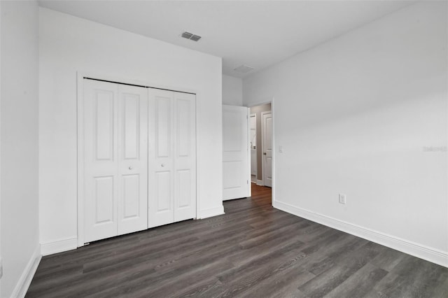 unfurnished bedroom featuring a closet and dark hardwood / wood-style floors