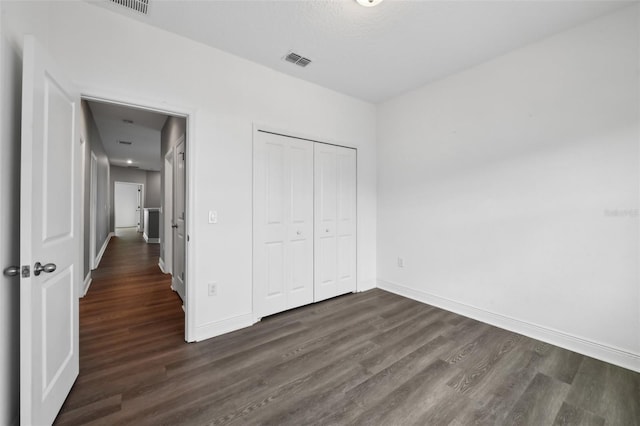 unfurnished bedroom with a closet and dark wood-type flooring