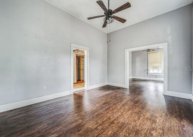 empty room with vaulted ceiling, ceiling fan, and dark wood-type flooring