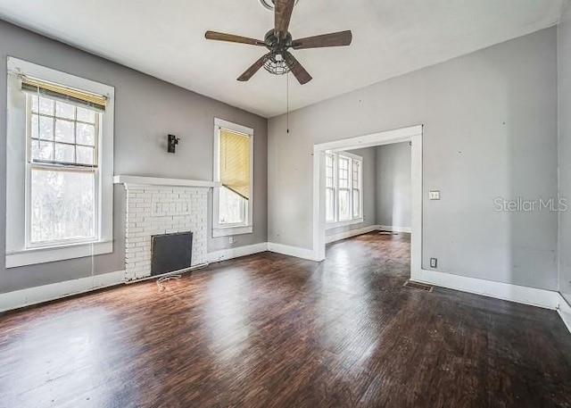 unfurnished living room with ceiling fan, dark hardwood / wood-style floors, and a brick fireplace