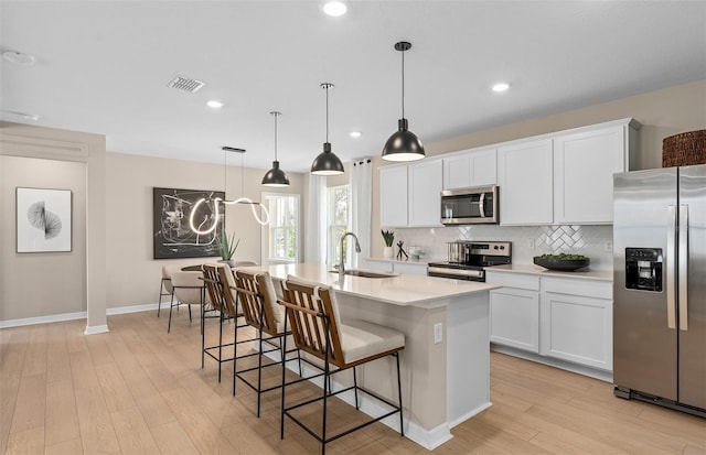 kitchen featuring white cabinetry, sink, appliances with stainless steel finishes, and an island with sink