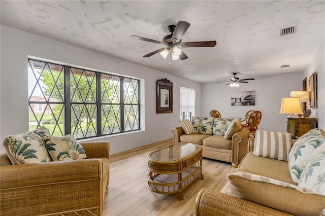 living room with light hardwood / wood-style floors, ceiling fan, and a healthy amount of sunlight