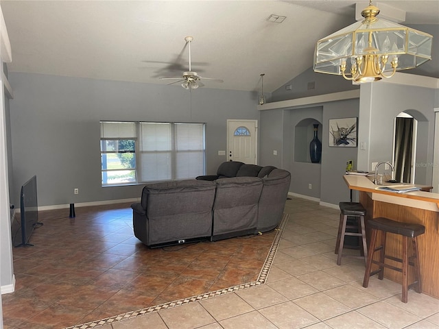 tiled living room featuring ceiling fan with notable chandelier and vaulted ceiling