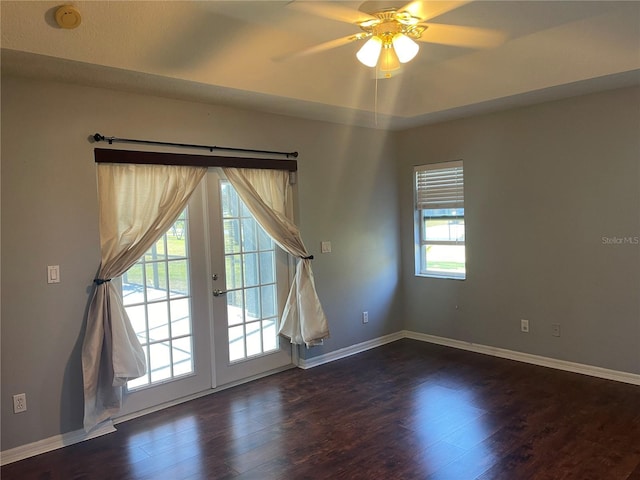 empty room with ceiling fan, dark hardwood / wood-style floors, plenty of natural light, and french doors