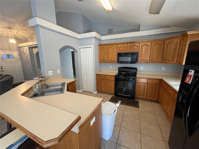 kitchen featuring sink, black appliances, light tile patterned floors, high vaulted ceiling, and an island with sink