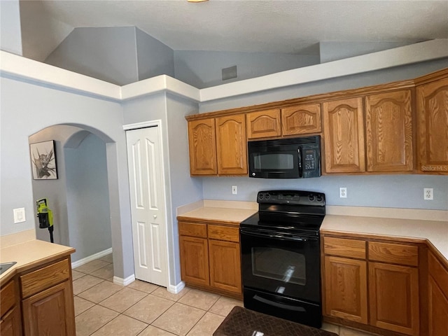 kitchen featuring black appliances, light tile patterned flooring, and high vaulted ceiling