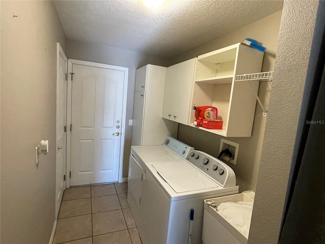 clothes washing area with cabinets, light tile patterned floors, washer and dryer, and a textured ceiling