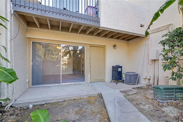 view of exterior entry featuring cooling unit and a patio area