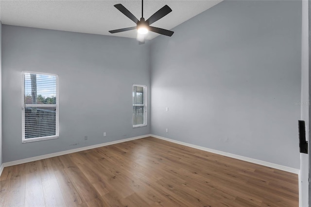 unfurnished room featuring wood-type flooring, a towering ceiling, a textured ceiling, and ceiling fan