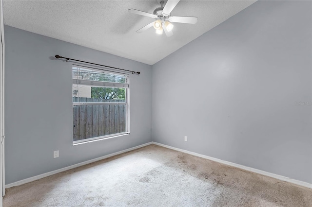 unfurnished room with ceiling fan, vaulted ceiling, carpet floors, and a textured ceiling