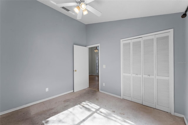 unfurnished bedroom featuring vaulted ceiling, light colored carpet, a closet, and ceiling fan