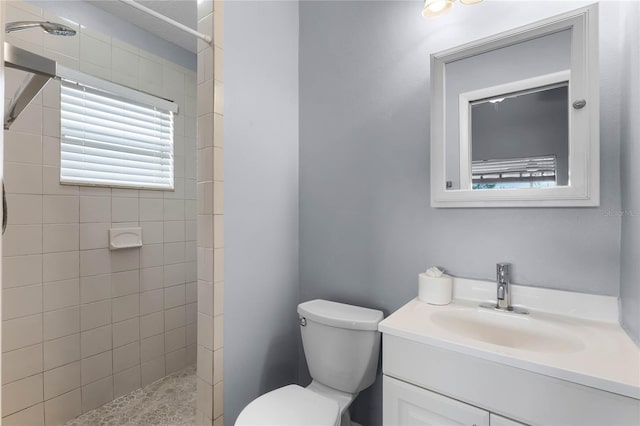 bathroom with vanity, toilet, and tiled shower