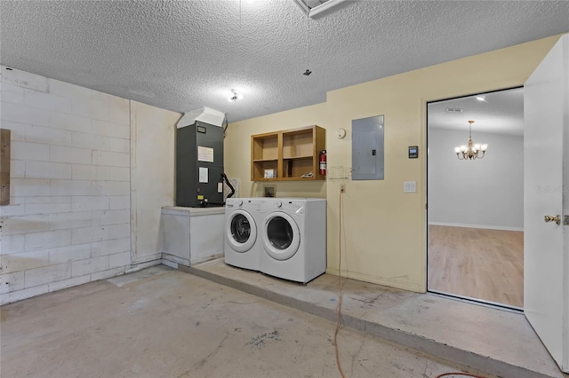 washroom featuring washing machine and dryer, a chandelier, electric panel, and a textured ceiling