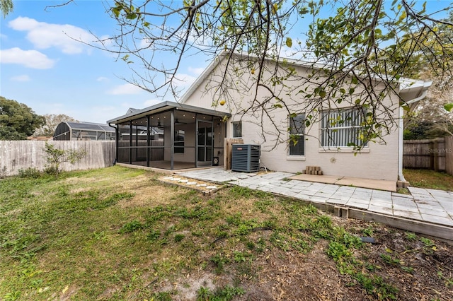 rear view of property with a sunroom, a yard, cooling unit, and a patio area