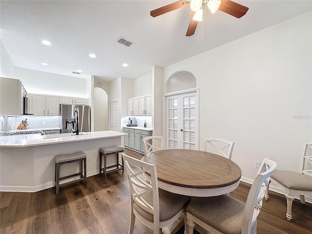 dining area with arched walkways, dark wood-style flooring, visible vents, and baseboards