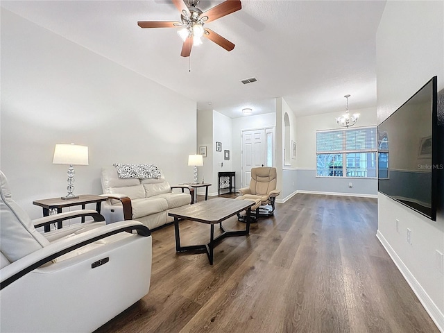 living room featuring ceiling fan with notable chandelier, dark wood-type flooring, visible vents, and baseboards