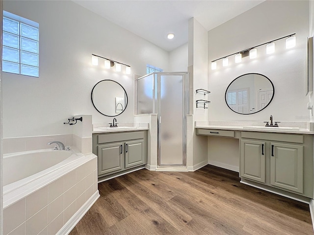 full bathroom featuring a garden tub, two vanities, a sink, a shower stall, and wood finished floors