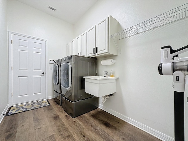 clothes washing area with dark wood-style flooring, visible vents, baseboards, independent washer and dryer, and cabinet space