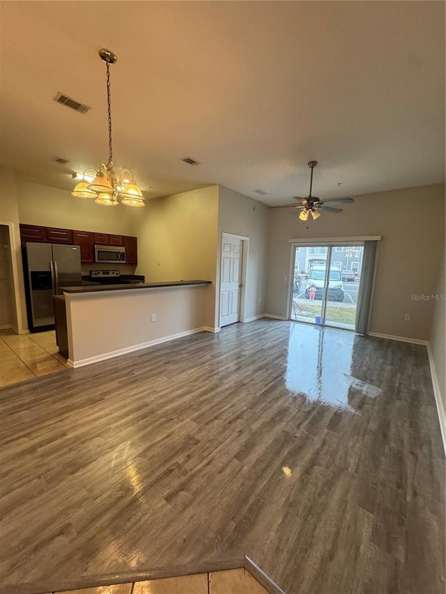 unfurnished living room featuring wood-type flooring and ceiling fan with notable chandelier