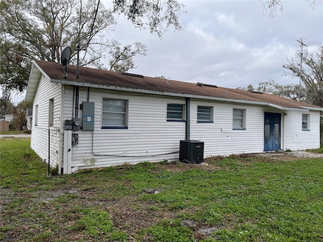 back of property featuring a lawn and central air condition unit