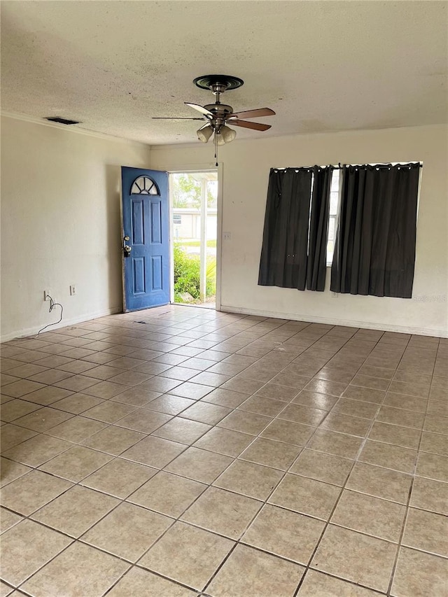 unfurnished room with ceiling fan, light tile patterned floors, and a textured ceiling