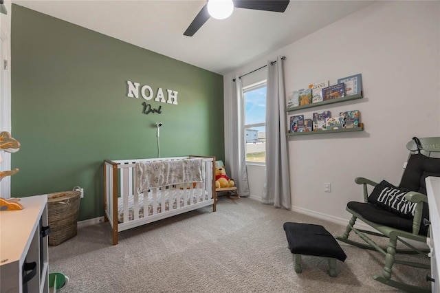 bedroom with a nursery area, ceiling fan, and carpet flooring