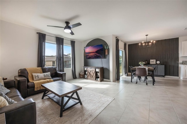 living room featuring wood walls and ceiling fan with notable chandelier