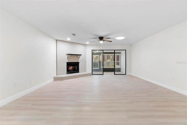 unfurnished living room with ceiling fan, light wood-type flooring, and a fireplace