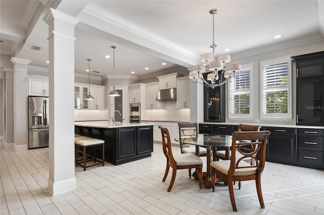 dining area with ornate columns, ornamental molding, sink, and a notable chandelier