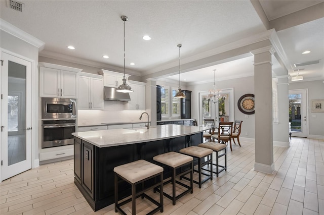 kitchen featuring sink, a breakfast bar area, appliances with stainless steel finishes, a kitchen island with sink, and white cabinets