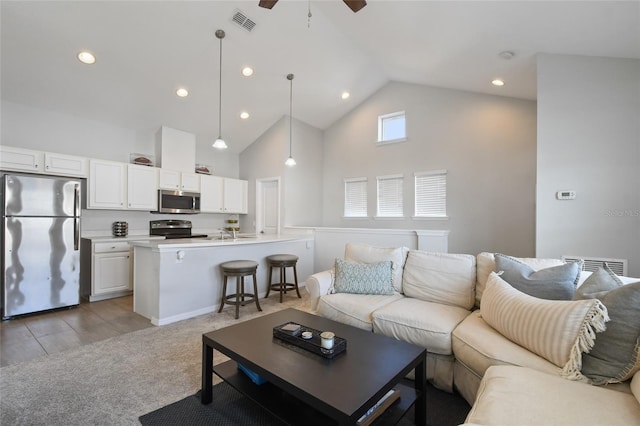 living room featuring light carpet, sink, high vaulted ceiling, and ceiling fan