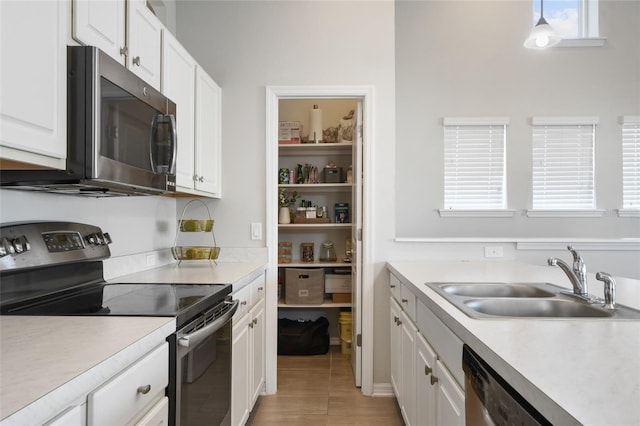 kitchen featuring sink, decorative light fixtures, light tile patterned floors, appliances with stainless steel finishes, and white cabinets