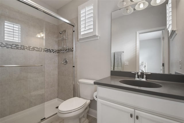 bathroom featuring a healthy amount of sunlight, toilet, a shower with door, and vanity