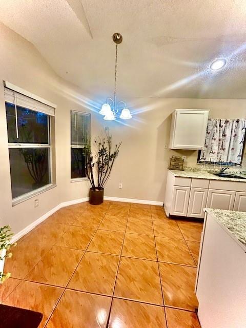 unfurnished dining area featuring an inviting chandelier, vaulted ceiling, a textured ceiling, and light tile patterned flooring