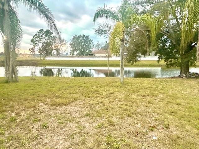 surrounding community with a water view and a yard