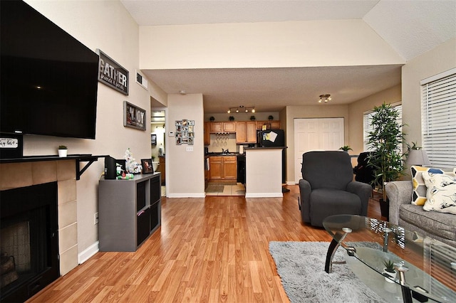 living room featuring a textured ceiling, light wood-type flooring, and a fireplace