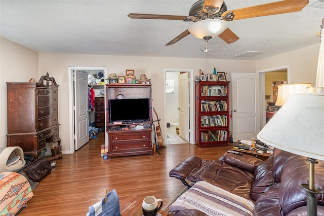 living room with ceiling fan, wood-type flooring, and a textured ceiling