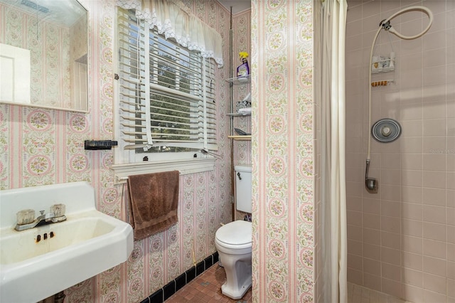 bathroom with tile patterned flooring, tiled shower, sink, and toilet