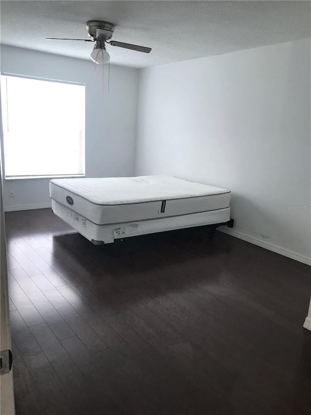 unfurnished bedroom featuring dark hardwood / wood-style flooring and ceiling fan