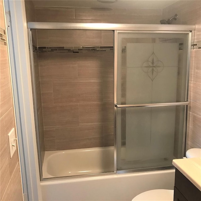 full bathroom with vanity, toilet, enclosed tub / shower combo, and tile walls