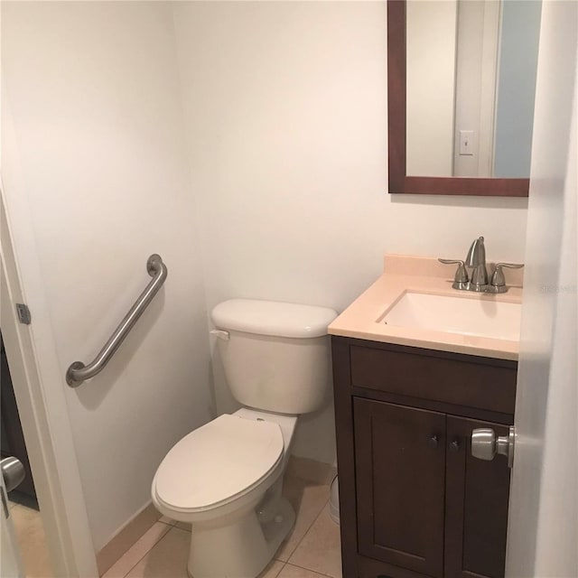 bathroom with toilet, vanity, and tile patterned floors